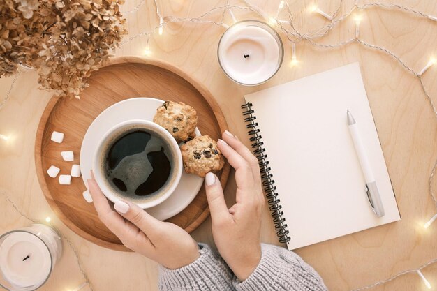 Ręka trzymająca filiżankę i notatnik